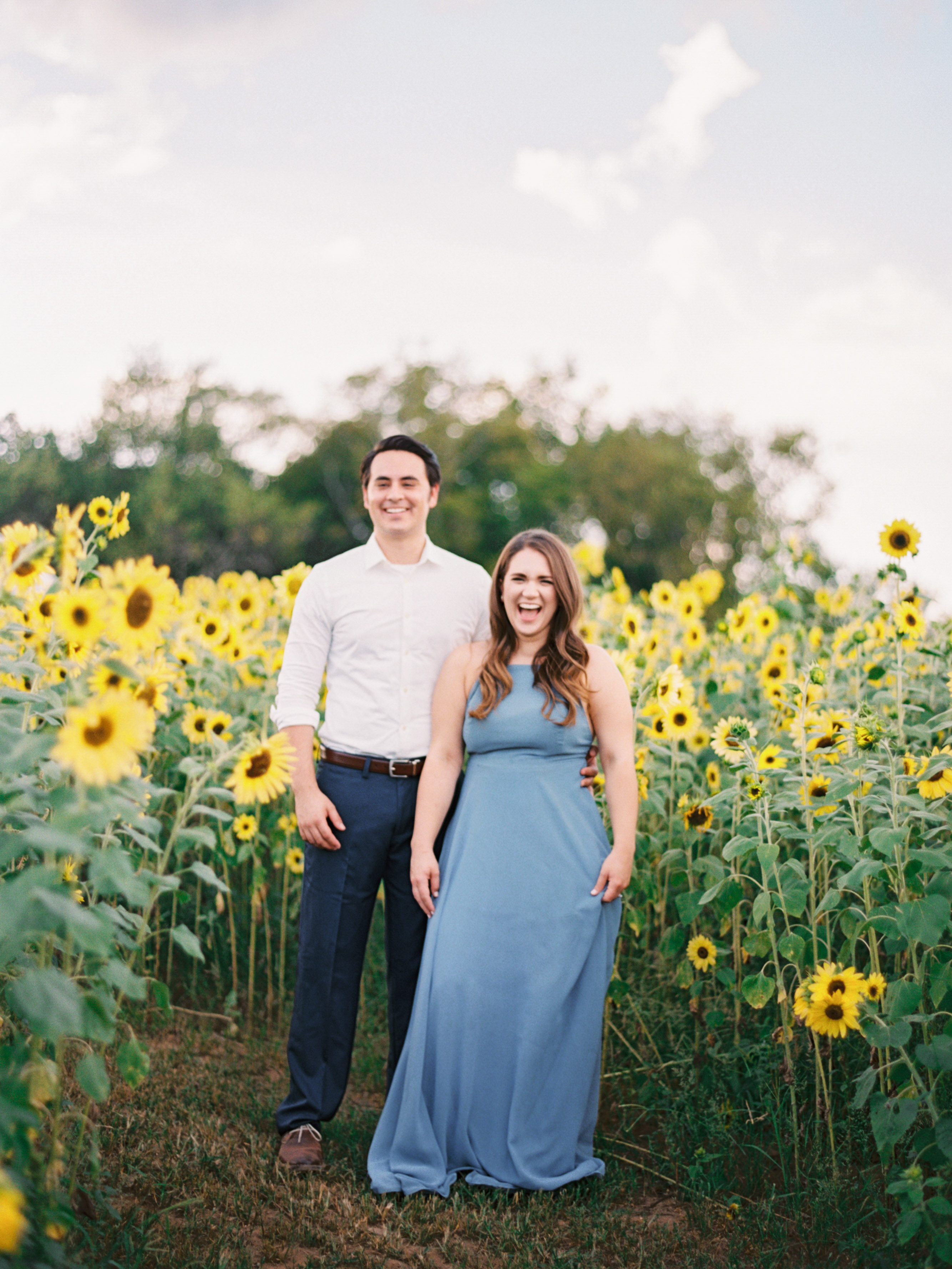 couple belly laughing in sunflowers