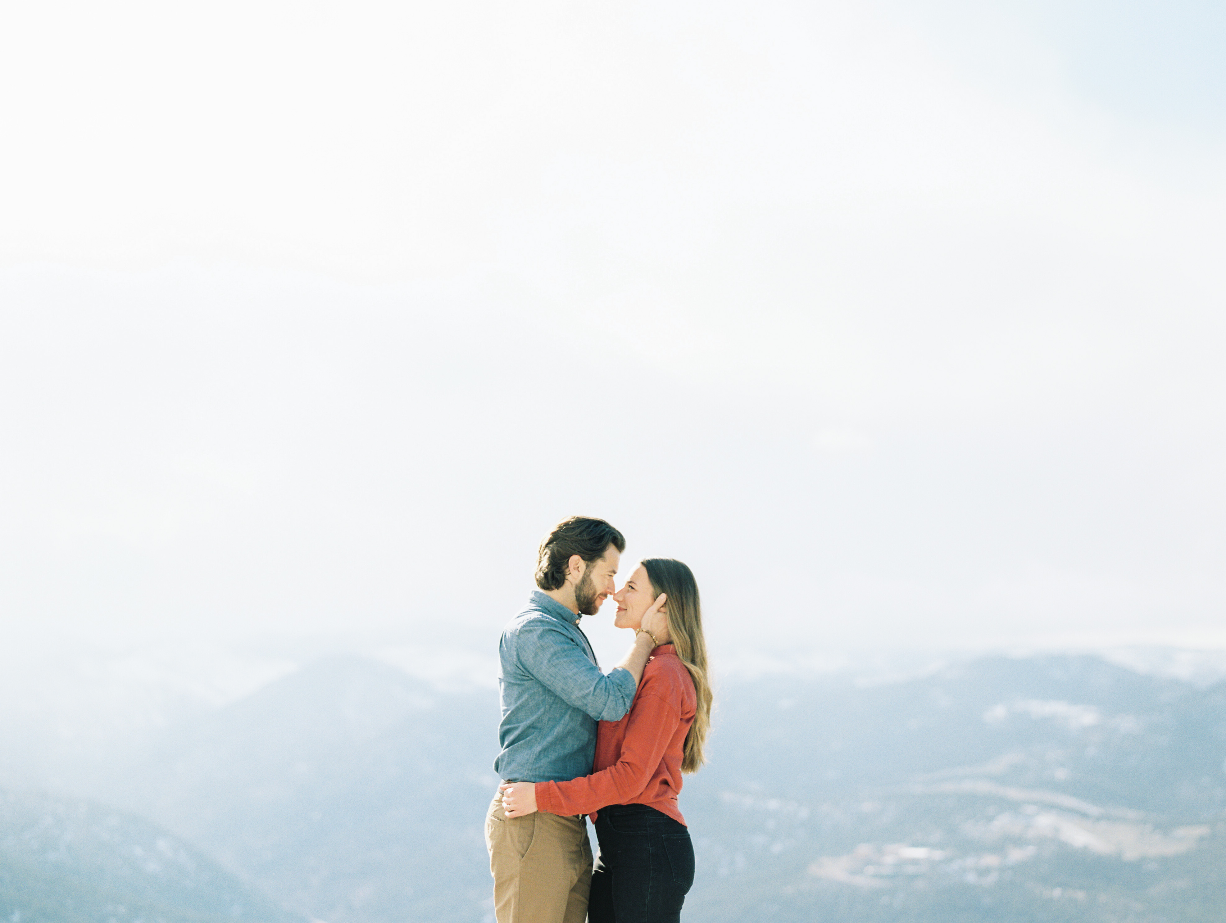 couple almost kissing overlooking mountain range