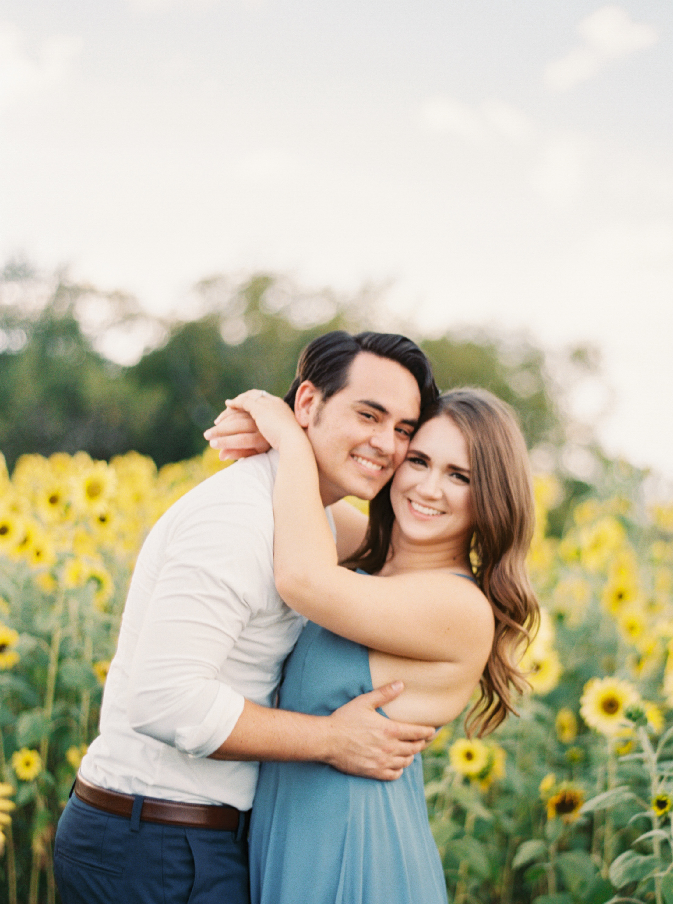 couple holding and smiling in sunflowers
