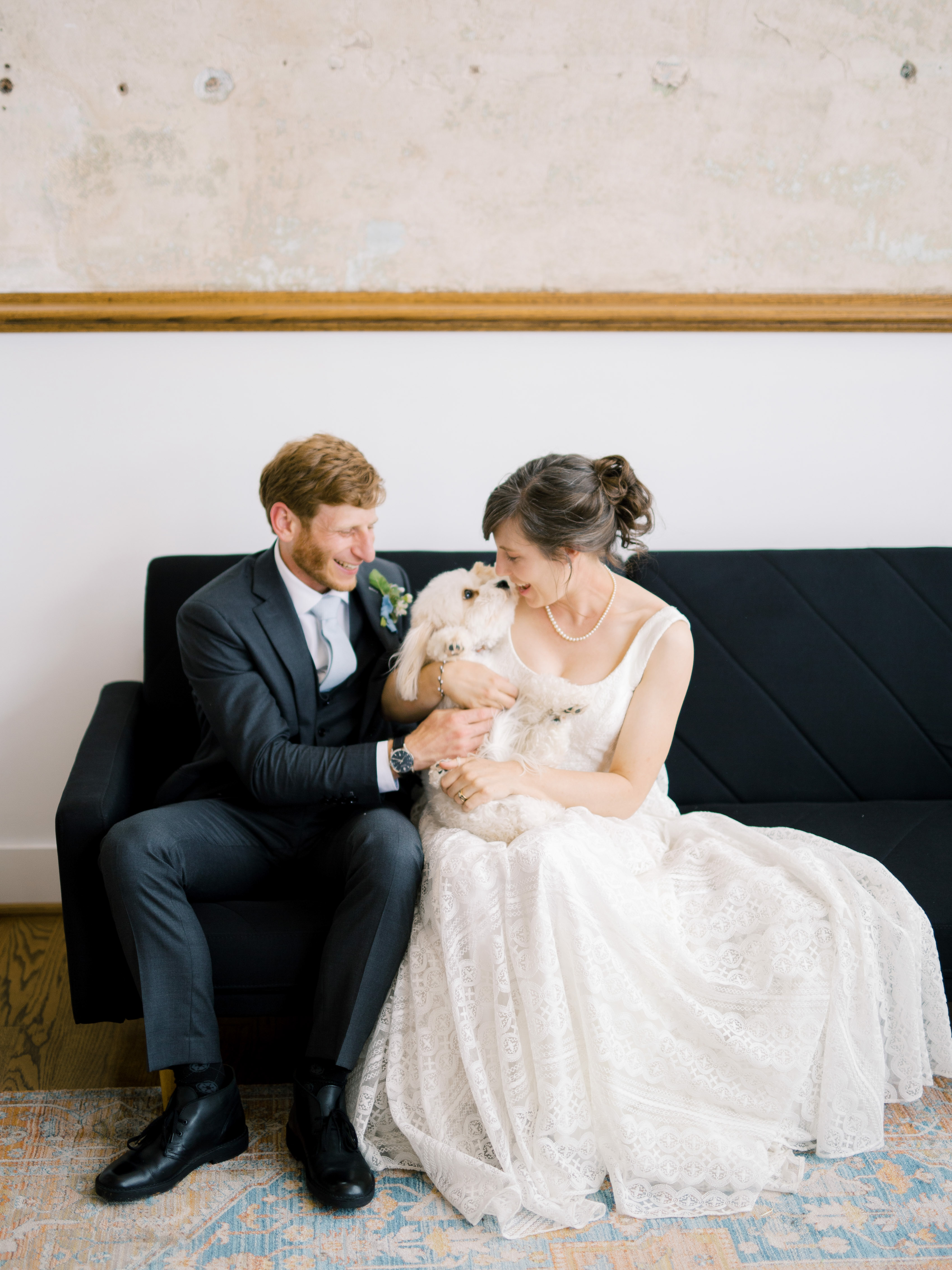 bride and groom happily playing with their pup