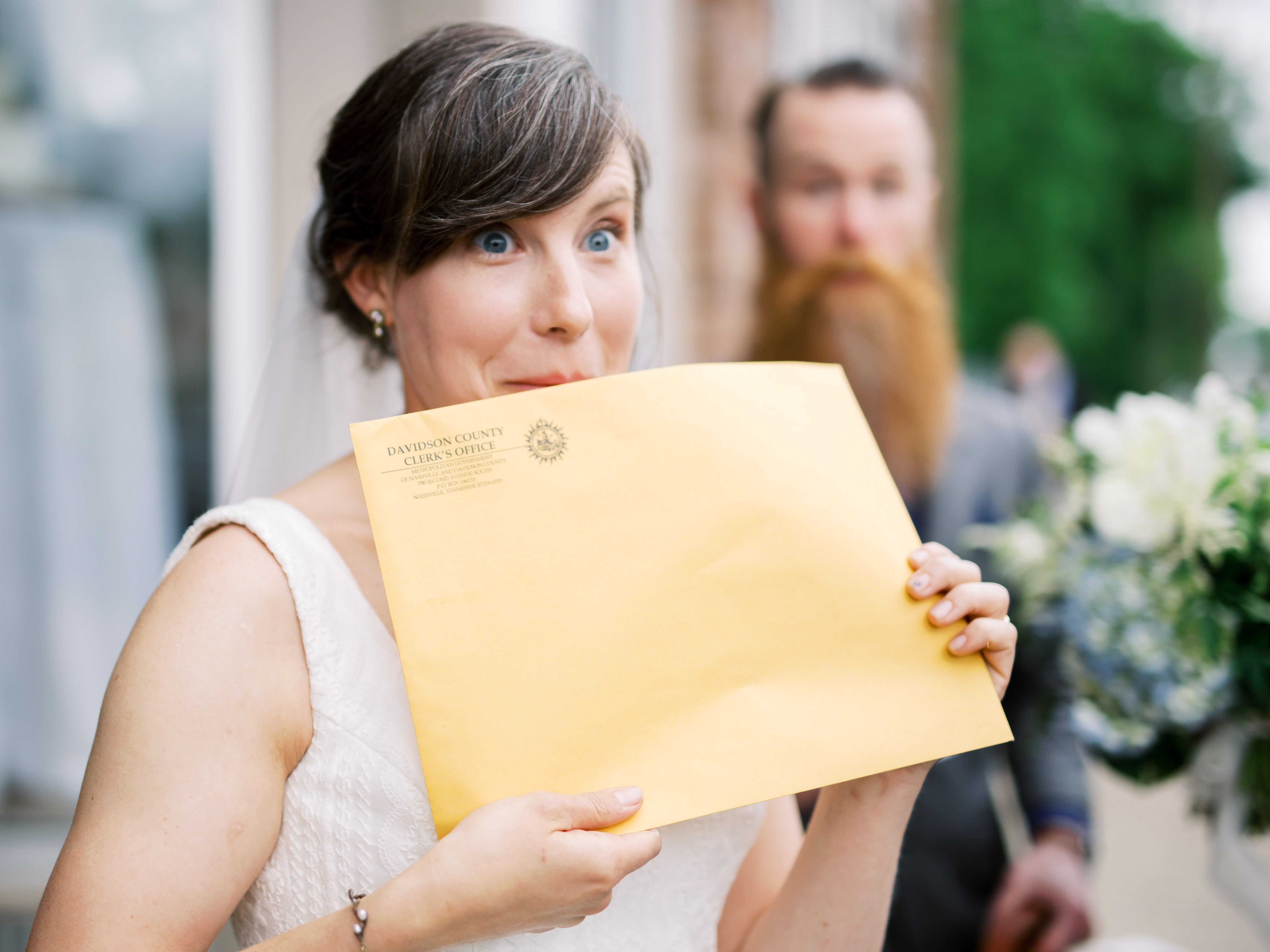 bride making funny face as she holds up marriage license