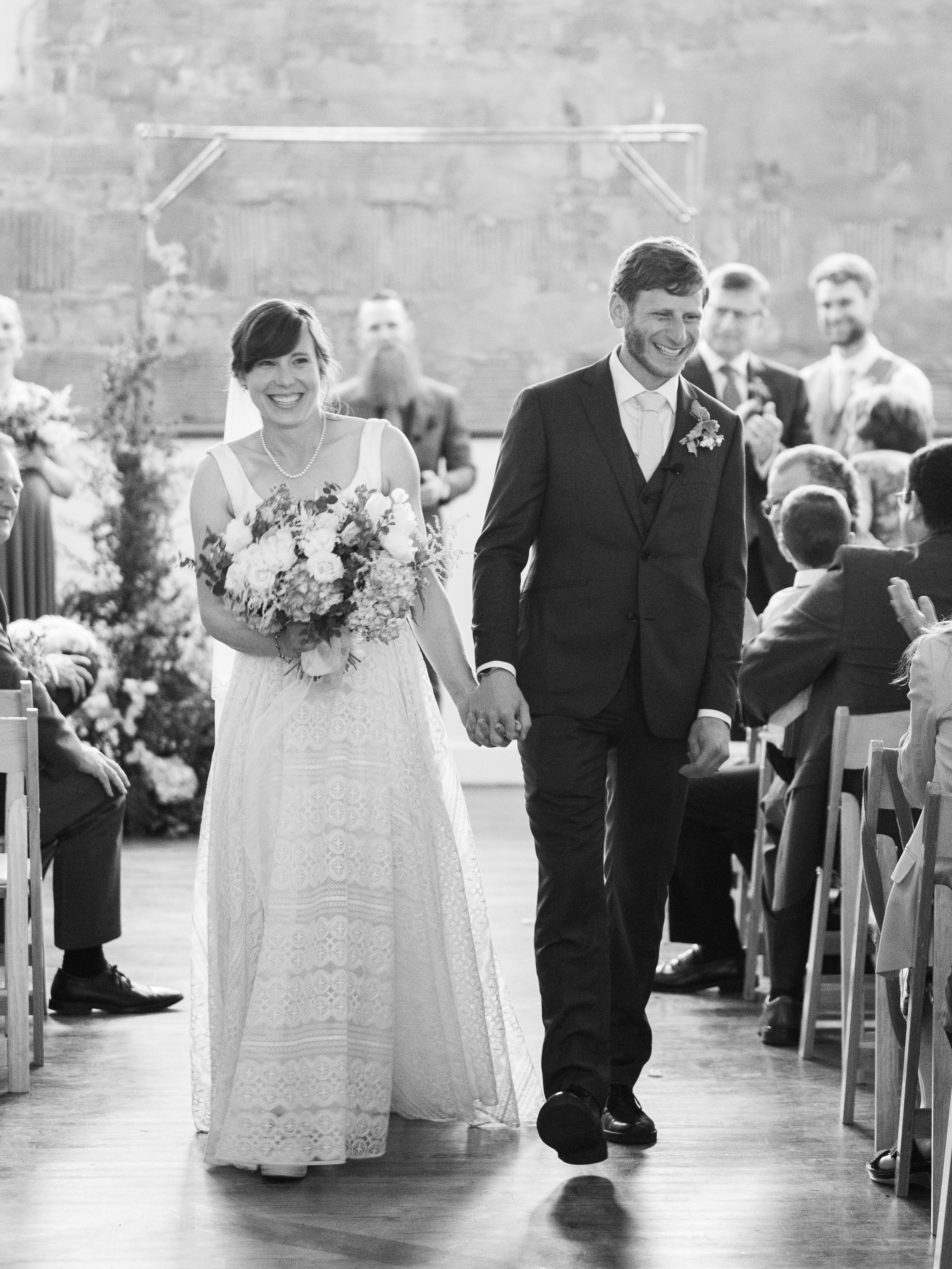 bride and groom laughing walking down the aisle just married