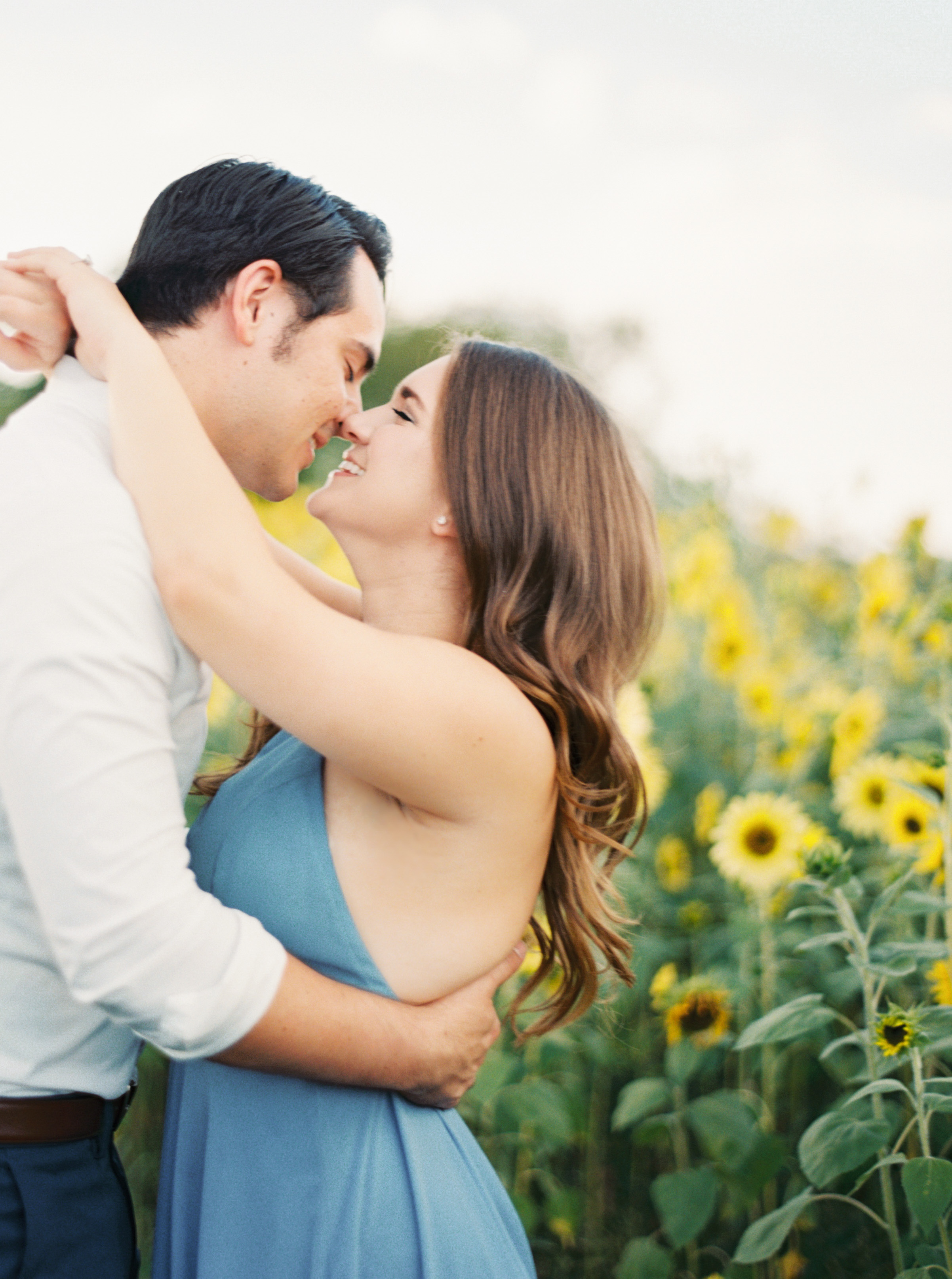 couple almost kissing in sunflower field